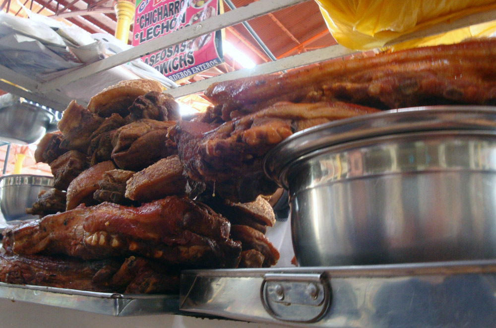 Image of Piles of roasted pork at one of the many vendors at Mercado San Camilo